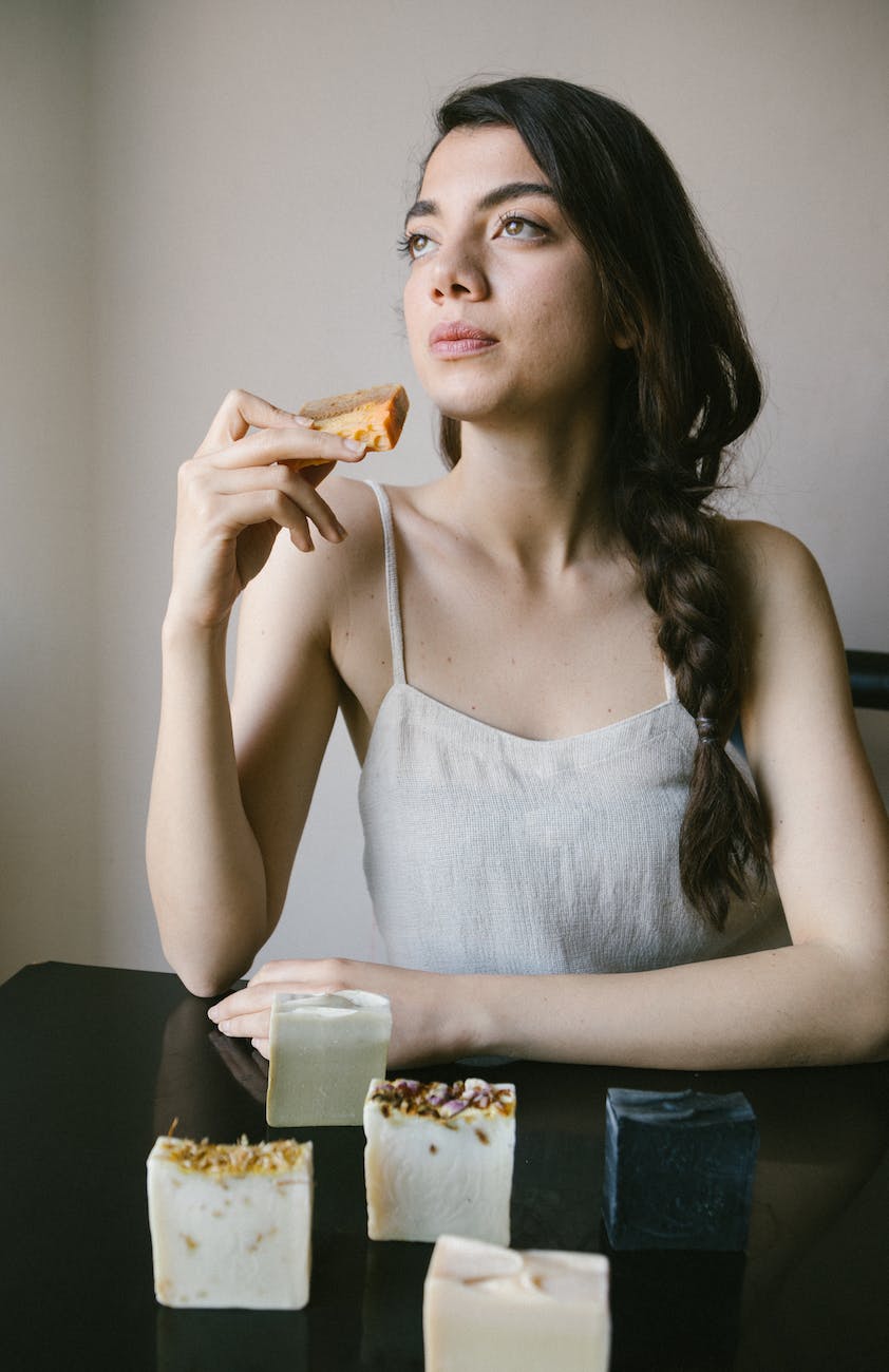 woman in white spaghetti strap top holding handmade bar soap